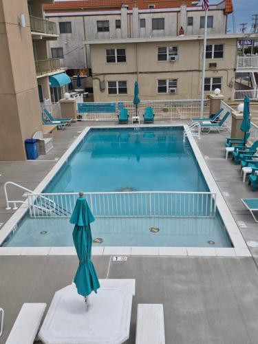 a swimming pool with an umbrella in front of a building at Aquarius Oceanfront Inn in Wildwood