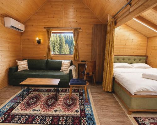 a bedroom with a bed and a couch and a table at Malesia Eko Resort in Peje
