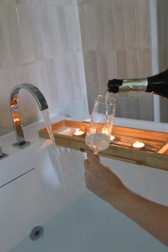 a person is pouring a glass in a bath tub at Le Nid du Cortil in Theux