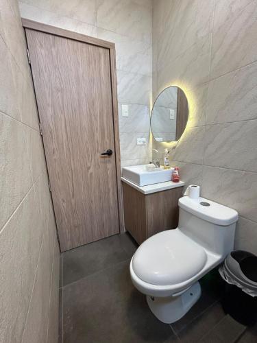 a bathroom with a toilet and a sink and a mirror at FinlandHouse in Puerto López