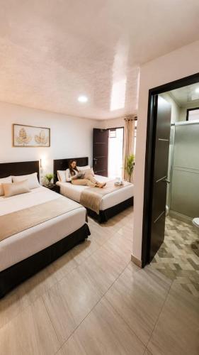 a hotel room with two beds and a woman laying on the bed at Hotel La Realeza in Barbosa