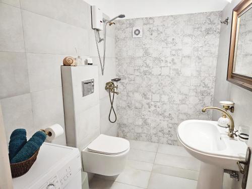 a white bathroom with a toilet and a sink at Lemon Nest in Marathokampos