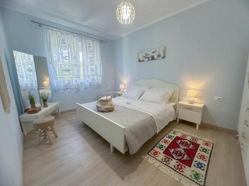 a bedroom with a white bed and two tables and two windows at Parkview Home in Korçë