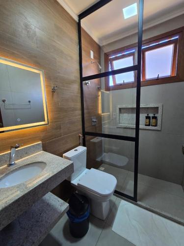 a bathroom with a toilet and a sink and a mirror at Pousada Portal da Barra in Marataizes