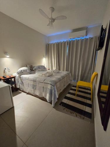 a bedroom with a bed and a window with a fan at Pousada Portal da Barra in Marataizes