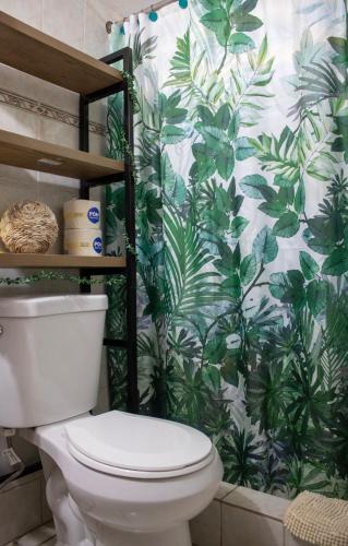 a bathroom with a toilet with a tropical wallpaper at Boquerón Beach & Country Cabins in Boqueron