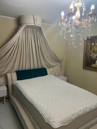a bedroom with a white bed with a chandelier at Casa verde in Săcălaz