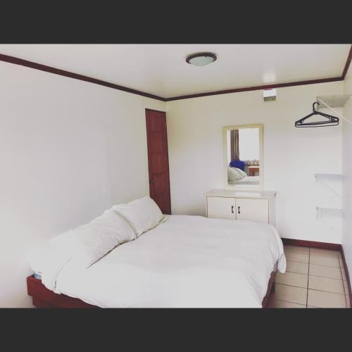 a bedroom with a white bed and a window at Casa Kibi Kibi in San José