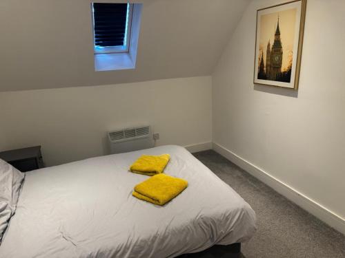 a bedroom with a bed with yellow towels on it at Epsom High Street Apartment 9 in Epsom