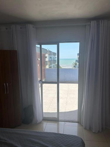 a bedroom with a view of the beach through a sliding glass door at COBERTURA Duplex com Visao do Mar, Village das ondas in Piúma