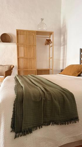 ein Schlafzimmer mit einem Bett, auf dem eine grüne Decke liegt in der Unterkunft Is Scabas Guestrooms in Solarussa