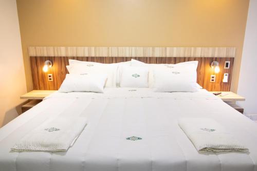 a large white bed with white towels on it at Los Olivos Hotel in San Estanislao