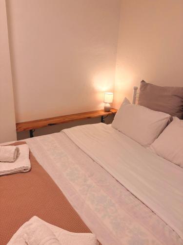 a bedroom with a large white bed and a lamp at Port Breeze Apartments in Karlovasi