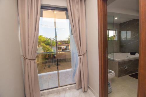 a bathroom with a tub and a toilet and a window at Los Olivos Hotel in San Estanislao