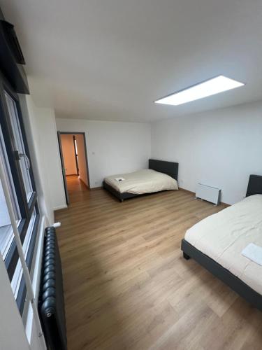 a bedroom with two beds and a wooden floor at Maison 3 chambres in Strasbourg