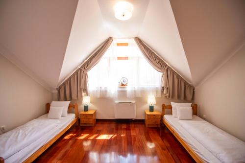 two beds in a attic room with a window at Mooi Panzió in Nagyatád