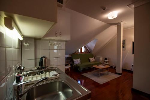 a kitchen with a sink and a living room at Mooi Panzió in Nagyatád