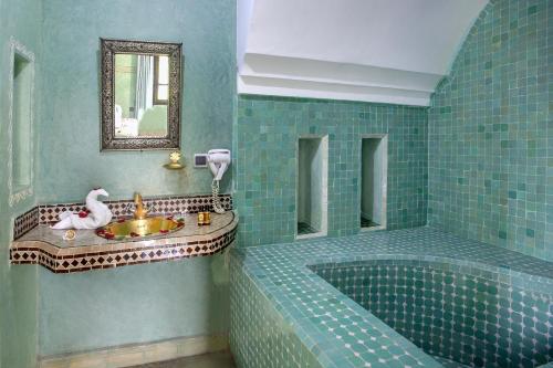 a green tiled bathroom with a tub and a sink at Domaine Ghait in Had Abdallah Rhiat