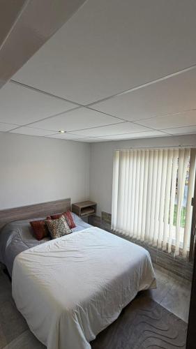 a bedroom with a large bed with white sheets and windows at departamento familiar 2 in Malargüe