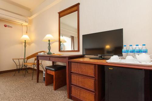 a hotel room with a desk with a television and a mirror at Hoya Hotel in Wenquan