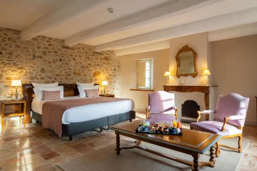 a bedroom with a bed and two chairs and a table at Hôtel - Restaurant & Spa La Magdeleine - Mathias Dandine in Gémenos