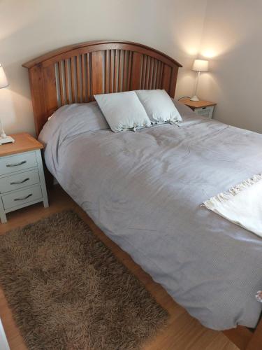 a large bed with a wooden headboard and a rug at Coastal Apartment in Malahide