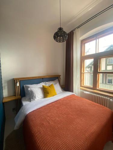 a bedroom with a bed with a orange blanket and a window at SecondHomeViljandi Apartment in Viljandi