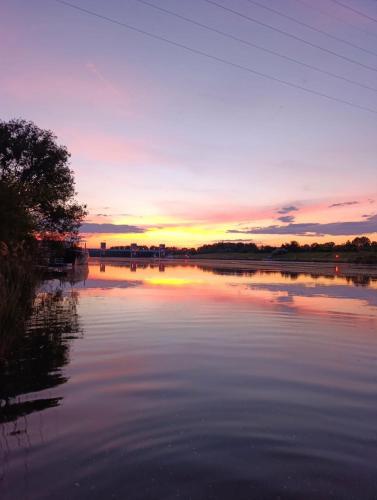 a sunset over a lake with the sun setting at Tisza Garden Park in Tiszalök