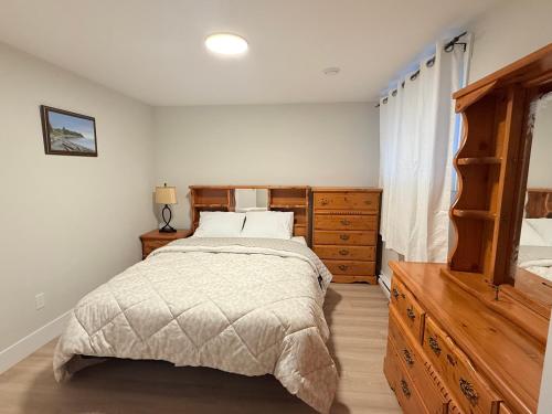 a bedroom with a large bed and a wooden dresser at Befitting Crown Suite in Moncton