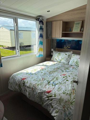 a bed in a small room with a window at Surf Shack Caravan - Lyons Winkups in Kinmel Bay