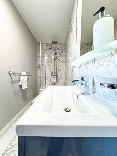 a white bathroom with a sink and a shower at Ocean View, 3 bed 2 bath, Dog Friendly, Private parking, Beach 9 min walk, sleeps 6 in Ilfracombe