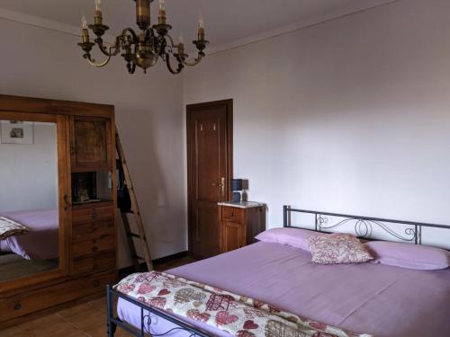 a bedroom with a bed with purple sheets and a chandelier at Da Poldino in Borgo a Buggiano