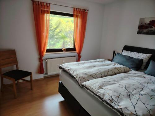 a bedroom with a bed and a window with orange curtains at Ferienwohnung Siegel in Heimweiler