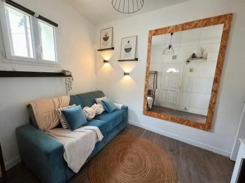 a living room with a blue couch and a mirror at *Ça me convient* Studio Chaleureux in Villejuif