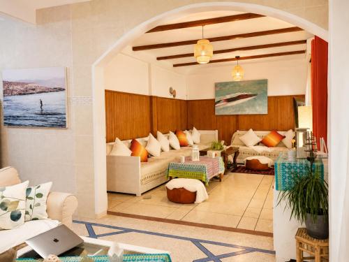a living room with a couch and a table with a laptop at HeenaluSurfCamp - ocean view appartement - 4P - Tamraght in Tamraght Ouzdar