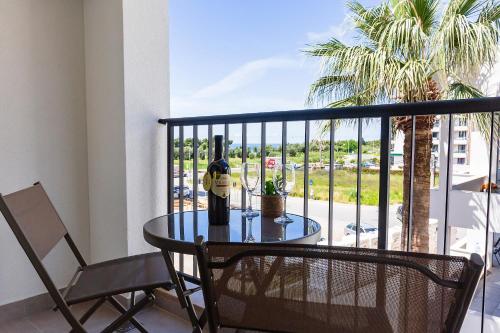 a table with a bottle of wine and a chair on a balcony at Seaside Premium Apartments Bar - Susanj in Bar