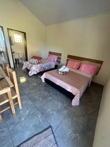 a room with two beds and a table in it at Chalé do coiote! in São Roque de Minas