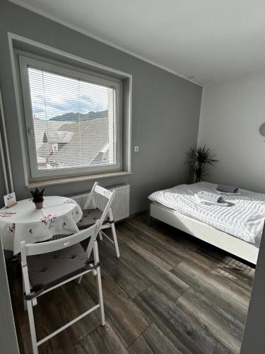a bedroom with a bed and a table and a window at Rooms Zima in Žirovnica
