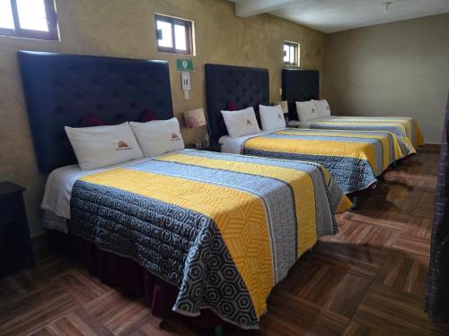 two beds in a room with yellow and blue at Hotel Milenio Nanacamilpa Tlaxcala in Nanacamilpa