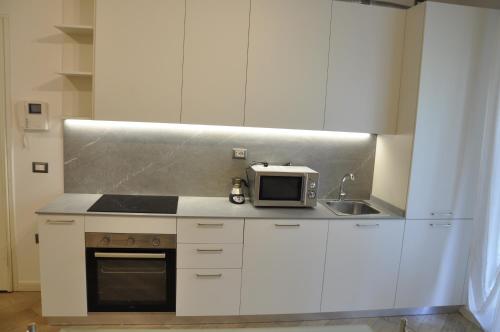 a white kitchen with a microwave and a sink at Appartamento moderno e spazioso con giardino privato in Selvazzano Dentro