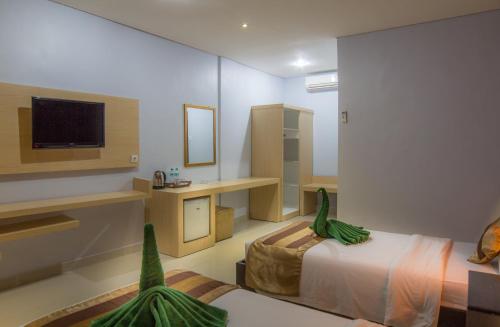 a room with a bedroom with a bed and a tv at Bakung Beach Resort in Kuta