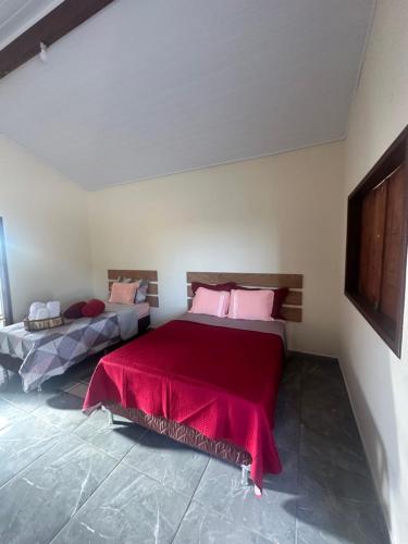 a bedroom with a bed with a red blanket at Chalé do coiote 2 in São Roque de Minas