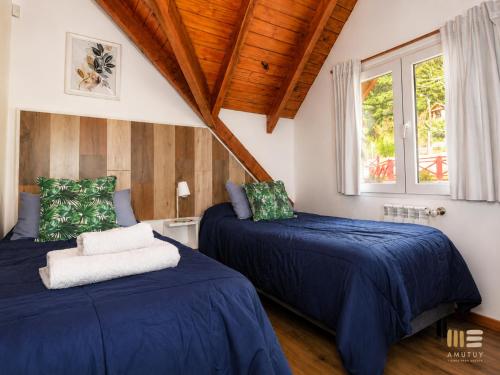 a bedroom with two beds with blue sheets and a window at Amutuy Bariloche in San Carlos de Bariloche