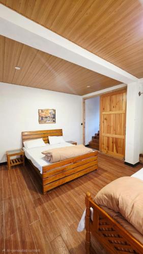 a bedroom with two beds and a wooden ceiling at Nathia Lodge Cottage in Nathia Gali