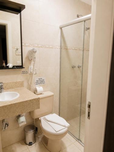 a bathroom with a toilet and a glass shower at Pousada Jasmim in Gramado