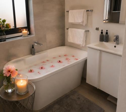 ein Badezimmer mit Badewanne, Waschbecken und Kerzen in der Unterkunft Flip-Flops studio in Hermanus