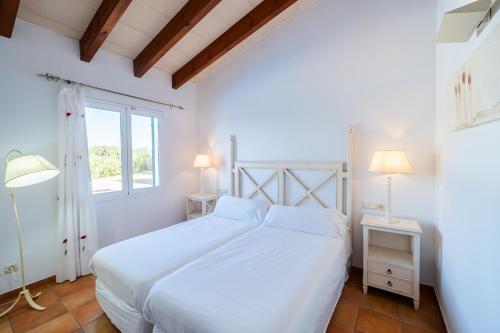 a white bedroom with a white bed and a window at Villas Finesse By MENORCARENTALS in Son Bou