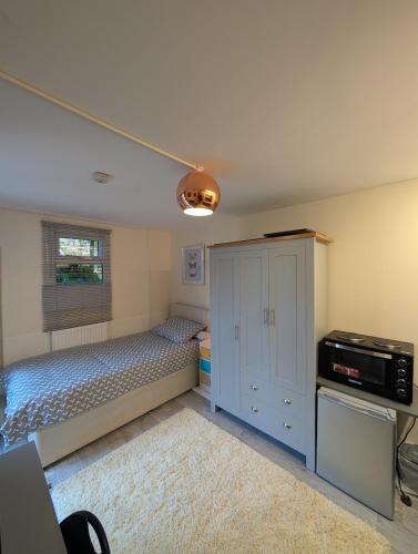 a bedroom with a bed and a cabinet and a window at Private Studio Anex in Sherborne Saint John