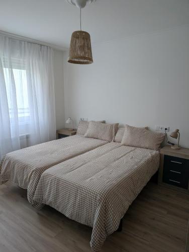 a white bedroom with a bed with a checkered blanket at Mosquera House in Arzúa