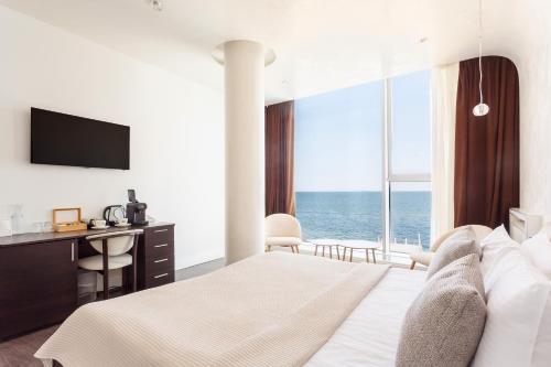 a bedroom with a bed and a desk and a large window at Boutique Hotel Portofino in Odesa